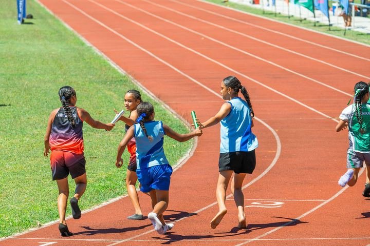 Relay teams exchange the baton on the bend.