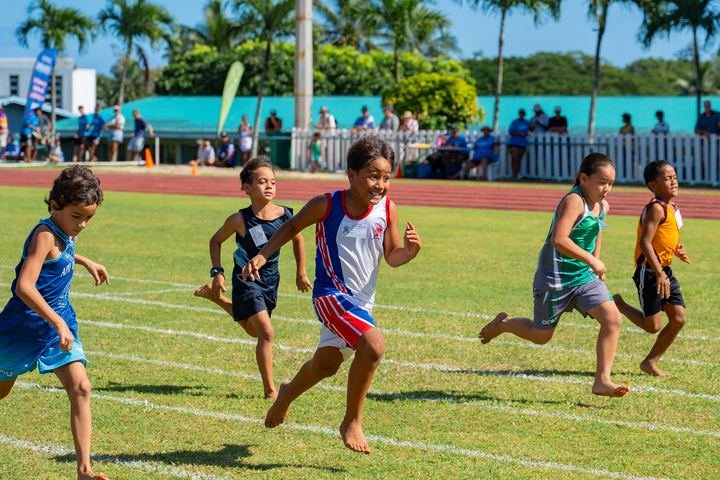 Young sprinters race barefoot on the grass track